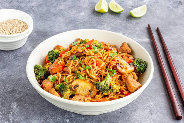 Ramen Noodles with Broccoli, Bell Pepper and Chicken in a Bowl with Chopsticks stock photo
