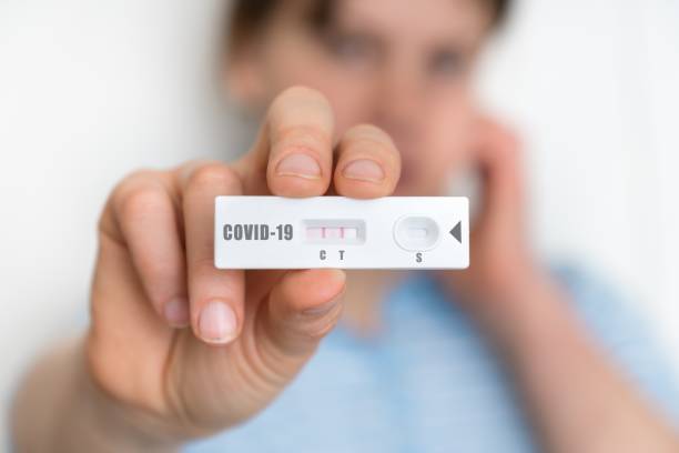 Rapid test on COVID-19 in hands of woman with positive result stock photo
