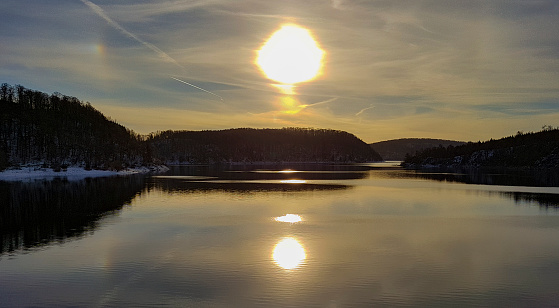 Rappode Dam, view of the dammed water. The setting sun is reflected in the water of the lake in winter time. Copy space
