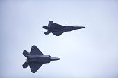 pair of F22 Raptor fighter jets flying in unison