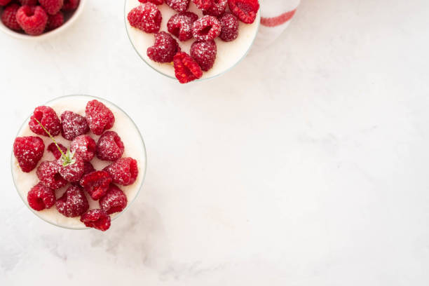 Raspberry dessert, raspberry tiramisu, cheesecake, trifle, mousse in a glass on a wooden background.Top view stock photo