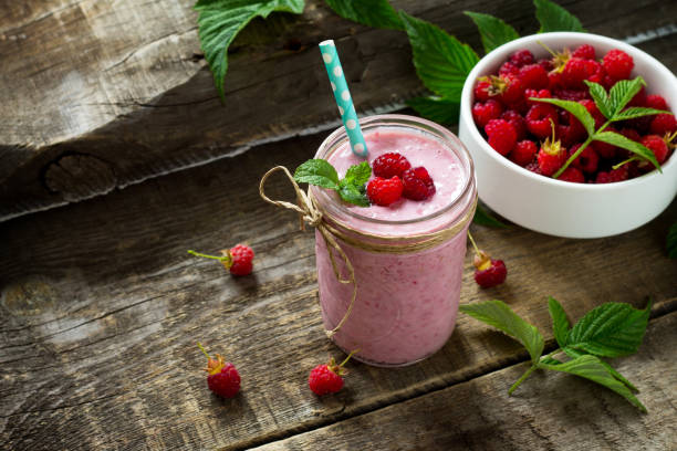 Raspberry fruit Yogurt smoothie or milk shake in glass jar on a wooden rustic table. Natural detox, fruit dessert, healthy dieting concept. Copy space. stock photo