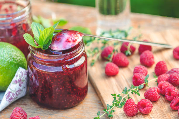 Raspberry jam and fresh raspberry on a rustic wooden table in the garden. stock photo