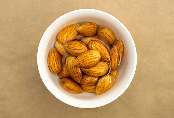 Raw almonds soaking in a white bowl of water Overhead closeup view of raw organic almonds soaking in a white bowl of fresh water caturbate stock pictures, royalty-free photos & images