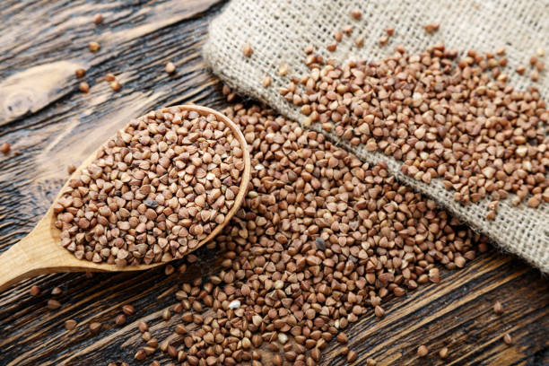 raw buckwheat groats on burlap on a wooden background. near a wooden spoon. stock photo