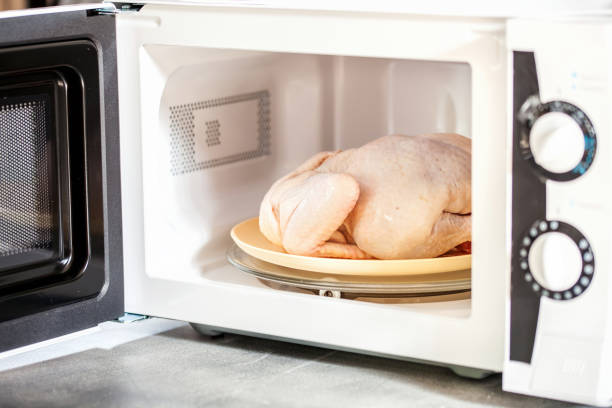 Raw chicken in the microwave stock photo