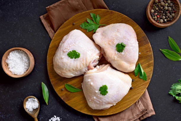 Raw chicken thigh on wooden cutting board Raw chicken thigh on wooden cutting board on dark background.Top view, flat lay chicken thigh meat stock pictures, royalty-free photos & images