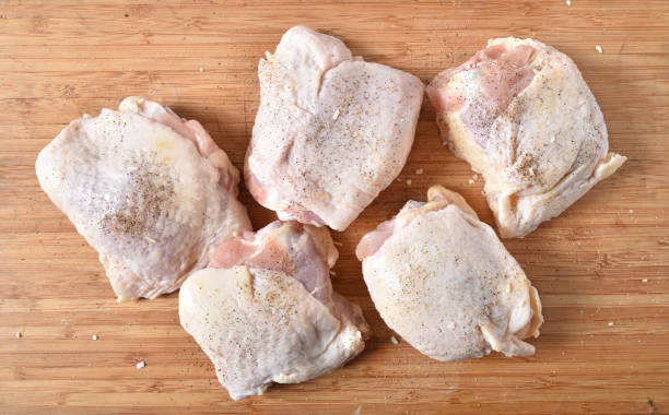 Raw chicken thighs Overhead view of chicken thighs prepared for cooking on a cutting board chicken thigh meat stock pictures, royalty-free photos & images