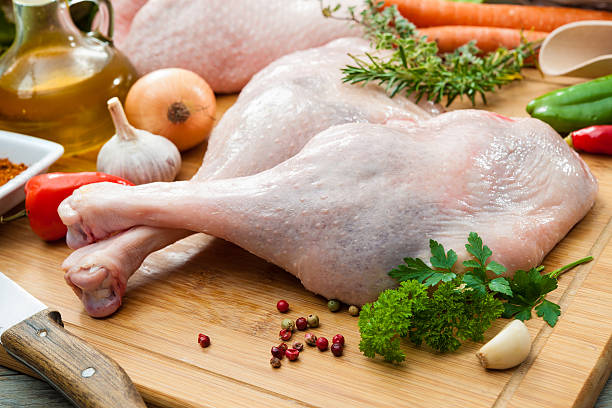 Raw goose legs on cutting board Preparation of goose legs at Christmas time goose meat photos stock pictures, royalty-free photos & images