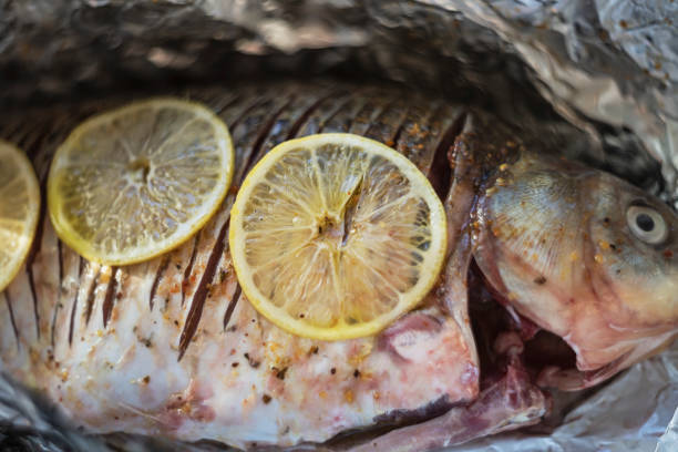 raw marinated fish with spices and lemons ready for roasting stock photo