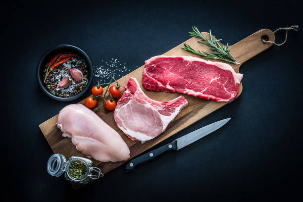 rauw vlees assortiment-rundvlees, kip en varkenskarbonades geschoten van bovenaf op donkere achtergrond - kip vlees stockfoto's en -beelden