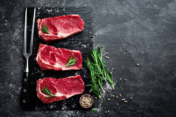 rauw vlees, biefstuk op zwarte achtergrond, bovenaanzicht - raw food stockfoto's en -beelden