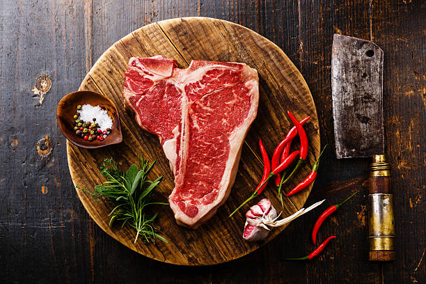 bistecca di carne cruda all'osso t, condimento e mannaia - fiorentina foto e immagini stock