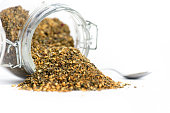 Raw Organic MIddle Eastern Zaatar Spices in a jar on white backgroud isolated. Za'atar is a culinary herb or family of herbs. It is also the name of a spice mixture that includes the herb along with toasted sesame seeds, dried sumac and salt