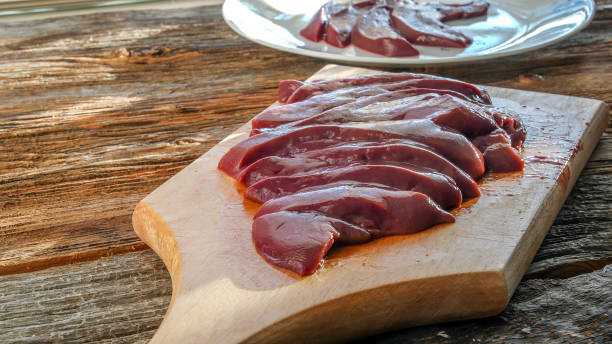 Raw pork liver on cutting board on rustic wooden table top stock photo