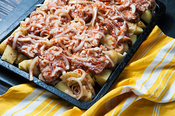 raw pork, onion and potatoes on a baking sheet - new barbecue sauce recipes 個照片及圖片檔