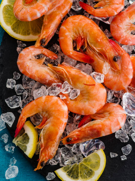 Raw prawns with lemon on ice. Raw prawns with lemon on ice, close-up prawn seafood stock pictures, royalty-free photos & images