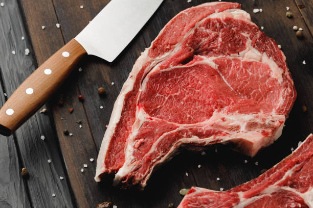 Raw rib eye steak on brown wooden board stock photo