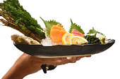 生サーモン刺身は、白い背景に隔離された氷の上に海藻、わさびレモンとデコレーションシェルを添え、日本の伝統的な食べ物