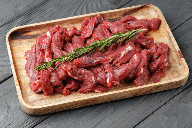 Raw sliced beef meat on wooden board stock photo