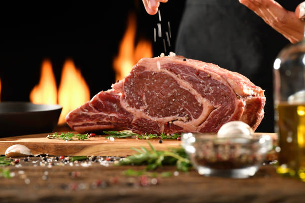 Raw steak meat beef on chopping board with flames on background stock photo