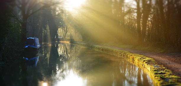 Ray of light on old canal in Bollington, Cheshire, England Early morning light breaking through the trees onto the canal near Bollington in Cheshire canal stock pictures, royalty-free photos & images