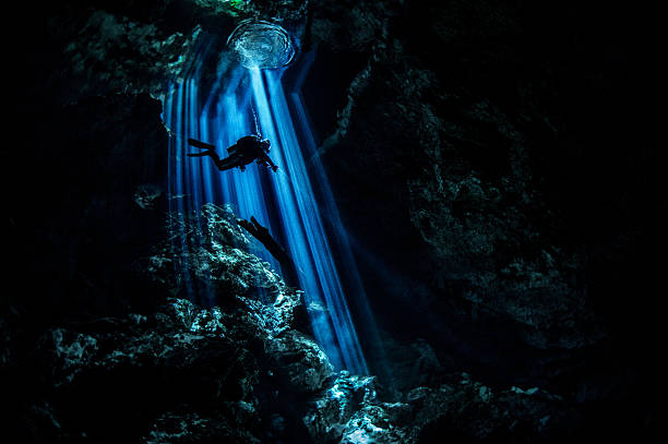 strahlen von licht in dunklen unterwasser-höhle - höhlenklettern stock-fotos und bilder