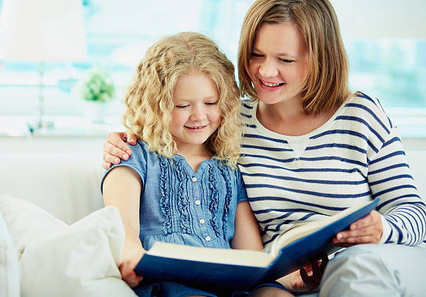Portrait of cute girl and her mother reading a book at home