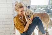 Photo of a young woman reading morning news online while her dog standing next to her