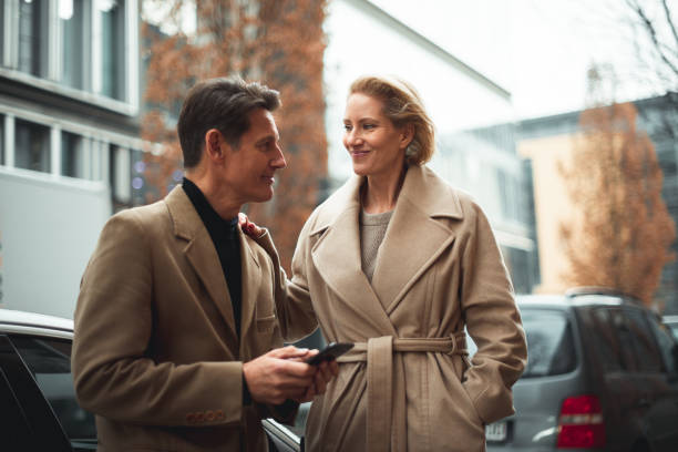 Ready for a trip Smart casual couple is standing next to their car ready to go for a road trip. He is holding a smartphone and they are looking at each other. georgijevic frankfurt stock pictures, royalty-free photos & images