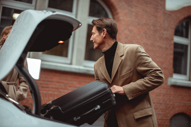 Ready for a trip Good looking 50-year-old man is putting luggage in the trunk of his car. georgijevic frankfurt stock pictures, royalty-free photos & images