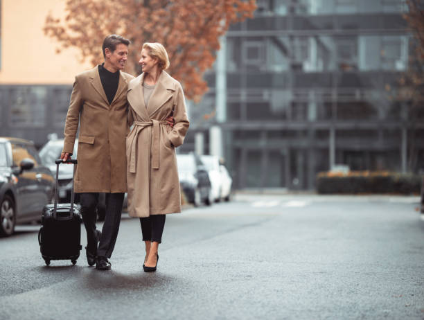 Ready to go Smiled smart elegant couple is walking down the street with a small elegant suitcase. georgijevic frankfurt stock pictures, royalty-free photos & images