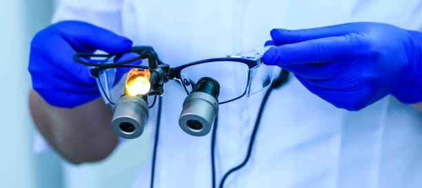 Real dental doctor holds the medical glasses with binocular lenses, in dentistry clinic. Dentist glasses or dental optic on a hospital medical laboratory. Modern technology equipment in surgery room. stock photo
