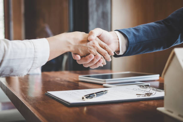 Real estate agent and customers shaking hands together celebrating finished contract after about home insurance and investment loan, handshake and successful deal stock photo
