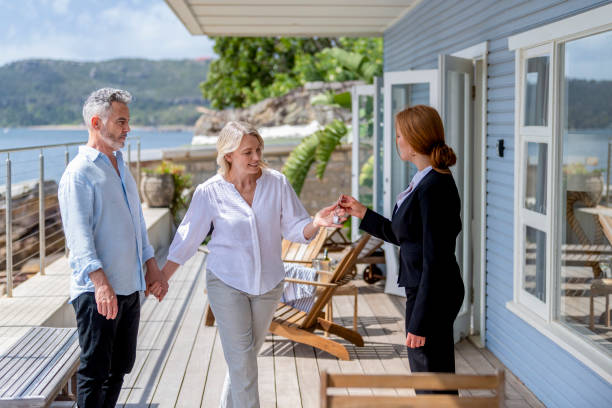 Real estate agent giving a mature couple the key to their new waterfront house. stock photo
