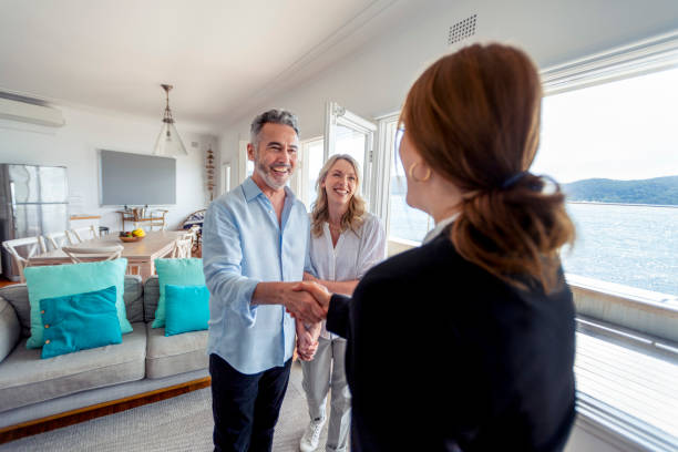 Real estate agent showing a mature couple a new house. stock photo