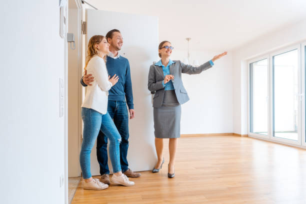 Real Estate Agent showing house to a young couple stock photo