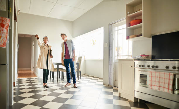 Real Estate Agent talking with a client in the kitchen of a house for sale Young female real estate agent talking with a client in the open plan kitchen of house for sale home inspection stock pictures, royalty-free photos & images