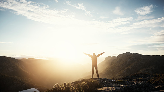 Shot of a young hiker standing with his arms outstretched on top of a mountain