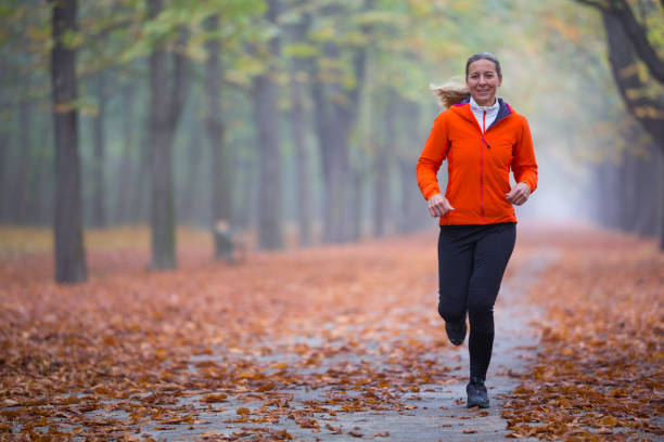 persone reali donna felice correre da sola nel parco la mattina d'autunno nebbiosa - autunno energia foto e immagini stock