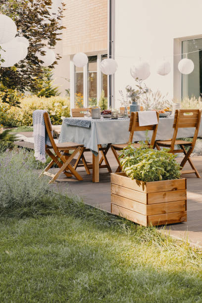 echtes foto eines gartens mit tisch, stühlen, lampen und holzkiste mit pflanzen - terrasse grundstück stock-fotos und bilder