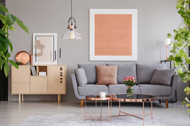 Real photo of a wooden cupboard next to a sofa in a modern living room interior with a big painting Real photo of a wooden cupboard next to a sofa in a modern living room interior with a big painting copper photos stock pictures, royalty-free photos & images