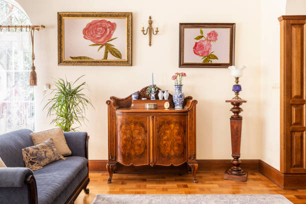 настоящая фо тография антикварного шкафа с фарфоровыми украшениями, картины с розами и синий диван в интерьере гостиной - антиквариат стоковые фото и изображения