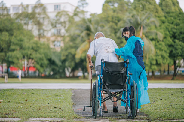 rear view asian chinese female physical therapist helping senior man get up from wheelchair and walking  in public park with crutch rear view asian chinese female physical therapist helping senior man get up from wheelchair and walking  in public park with crutch diabetic foot stock pictures, royalty-free photos & images