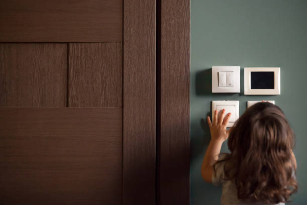 Rear view at little child girl playing turning light switches Rear view at little careless child girl exploring house playing turning light switches, home electricity danger security, electric shock risk and kids safety, energy power saving concept, copy space Smart switch stock pictures, royalty-free photos & images