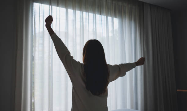 gambar tampilan belakang seorang wanita melakukan peregangan setelah bangun di kamar tidur - bangun pagi potret stok, foto, & gambar bebas royalti