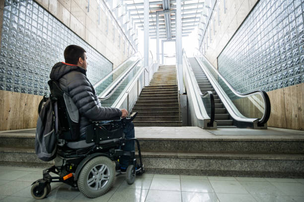 rear view of a disabled man on wheelchair in front of escalator and staircase with copy space - wheelchair street imagens e fotografias de stock