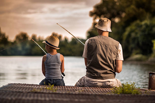 Rear view of a father and son freshwater fishing. stock photo