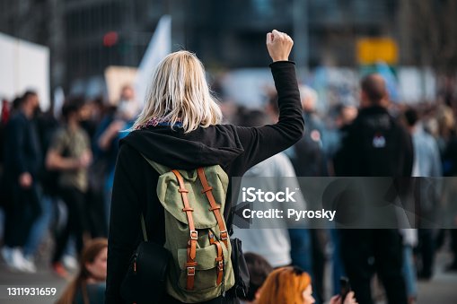 istock Rear view of a female protester raising her fist up 1311931659
