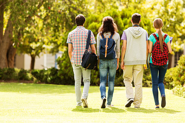 rear view of a student group walking on campus - alleen tieners stockfoto's en -beelden